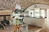 Rustic vaulted ceiling, designer furniture and traditional log burner in elegant country-house kitchen