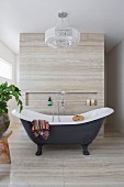 Freestanding vintage bathtub with stand mixer in designer bathroom with natural stone cladding