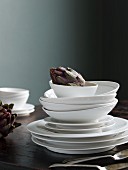 Stack of white plates and soup bowls on table