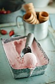 Berry ice cream in an ice cream container with an ice cream scoop