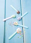 Various types of ice cream on ice cream spoons scattered with sugar sprinkles: vanilla, strawberry, chocolate, blueberry and mint
