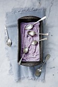 Blueberry ice cream in a loaf tin with silver spoons