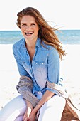 Junge brünette Frau in Jeanshemd mit Shirtjacke am Strand