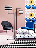Black armchair, designer standard lamp, blue chair on platform against wallpaper and mixture of patterns