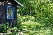 Holzhaus mit blauem Sprossenfenster im Sommergarten