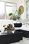 Bowl with colourful planting on black wicker coffee table in front of cosy couch