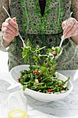 Woman mixing Tomato, Rocket and Pine Nut Salad