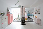 Offener Wohnraum mit Schwedenofen und pastellfarbenen Kleinmöbeln
