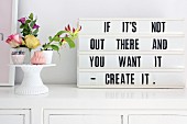 Retro-style motto in frame next to flower arrangement