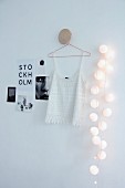 Spherical fairy lights next to white lace top and black and white pictures on wall