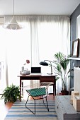 Retro Schreibtisch mit Klassikerstuhl und Zimmerpflanzen vor Fenster