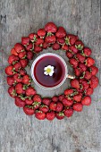 Eine Tasse Erdbeertee umrahmt von frischen Erdbeeren (Aufsicht)