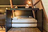 Fold-away bed in dark grey cupboard with open doors