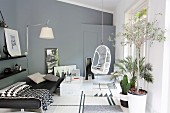 Couch, hanging chair, wall lamp and plants in modern living room in shades of grey