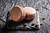 Macaroons with coffee beans on a black stone