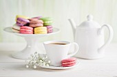 Colourful macaroons with coffee on a white table
