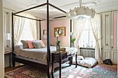 Bett mit Holzgestell in romantischem Schlafzimmer mit pastellrosa Wänden und geblümten Wohntextilien