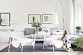 Sheepskins on white garden chairs, pale grey couch and designer standard lamp in lounge area