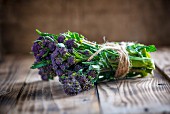 A bundle of purple sprouting broccoli on a wooden board