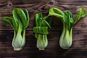 Three bok choy on a wooden board