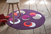 Runder, violetter Teppich aus Walkstoff mit aufgenähten unterschiedlichen, kontrastfarbigen Kreisen
