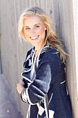 Junge blonde Frau in Top und blau-weisser Strickjacke