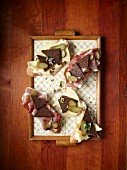 Pumpernickel slices topped with raw ham, cheese and gherkins