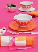Orange place settings and matching napkins on hot-pink tablecloth