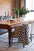 Rustic wooden table and upholstered chairs in front of brick wall