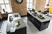 Kitchen islands with polished concrete work surfaces over black cupboards with cement floor tiles in a retro pattern