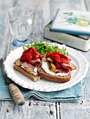 Slices of bread topped with pastrami, roasted peppers and gherkins