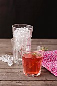 Fruchtsaft mit Thymianzweig und Crushed Ice in Gläsern