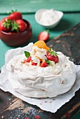 Pavlova with whipped cream, fruit and almonds