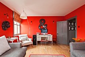 Schreibtisch und Armlehnsessel in renovierter Altbauwohnung mit roten Wänden