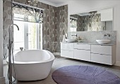 Free-standing bathtub and patterned wallpaper in elegant bathroom