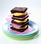 A stack of brownie sandwiches with mango cream