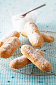 Sponge fingers with icing sugar on a wire rack