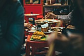 Menschen beim Essen mit Essstäbchen in Restaurant