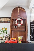 Aufgestelltes Holzboot an Wand mit Rettungsring und Lichterkette dekoriert hinter Küchentheke