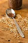 Oat seeds on a wooden surface with a spoon