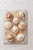 Various meringues with chocolate sauce and strawberries on a weathered wooden board