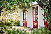 View of house with red doors seen through trees