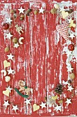 Rahmen aus weihnachtlicher Deko, Nüssen und Plätzchen auf rot-weißem Untergrund