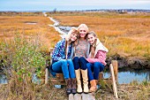 Mutter mit Töchter sitzt auf Steg am Ufer