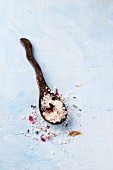 A wooden spoon with rose and lavender bath salt