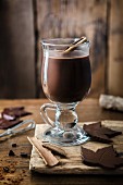 Ein Glas heiße Schokolade mit Zimt und Schokoladenblättern