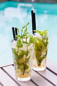 Two Mojitos on a table by a pool