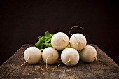 White turnips on a wooden surface against a black background