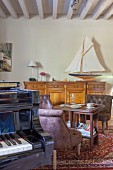 Piano, leather easy chairs and model sailing boat on top of sideboard in living area