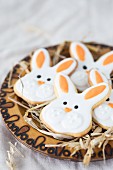 Easter bunny cookies on a wooden plate with straw